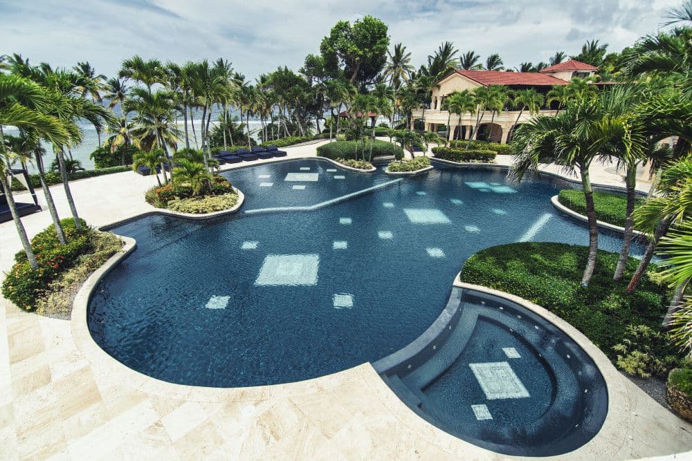 Freeform pool and spa with sun loungers and ocean views at Villa Anacaona