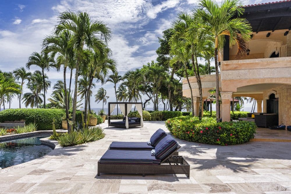 Poolside sun loungers and a daybed with sea views at Villa Anacaona