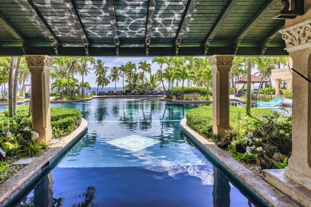 Pool and water feature framed by columns and orchids at Villa Anacaona