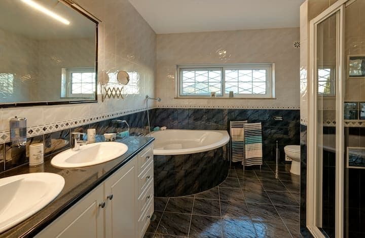 Bathroom with a corner tub and double vanity in dark tile at Citrus, Peppers & Palms, Algarve