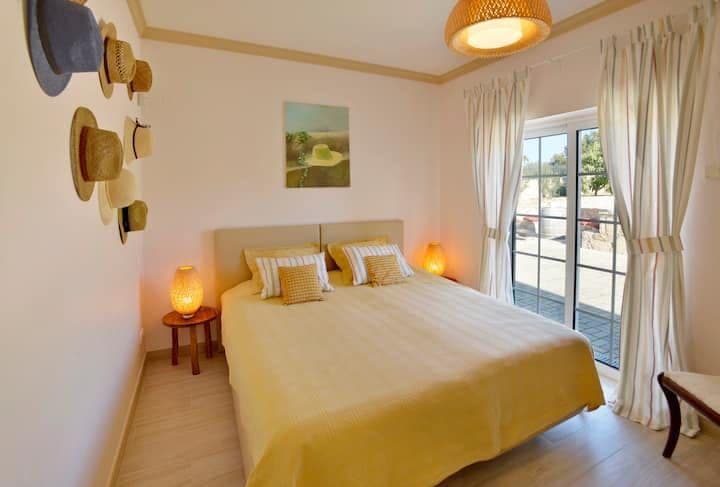 Double bedroom with yellow accents and a hats display opening to the terrace at Citrus, Peppers & Palms, Algarve