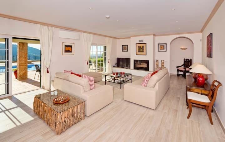 Living room with cream sofas and a fireplace opening to the pool terrace at Citrus, Peppers & Palms, Algarve