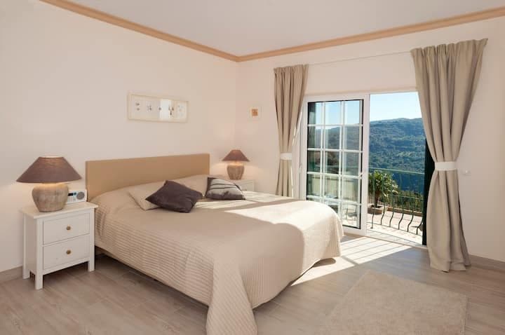 Master bedroom with a taupe headboard and doors to a hill-view balcony at Citrus, Peppers & Palms, Algarve