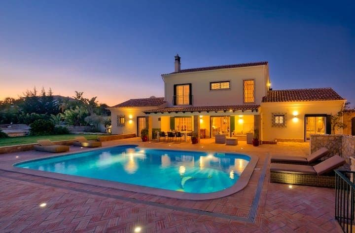 Algarve villa glowing at dusk beside its lit pool at Citrus, Peppers & Palms, Sao Bras de Alportel, Portugal