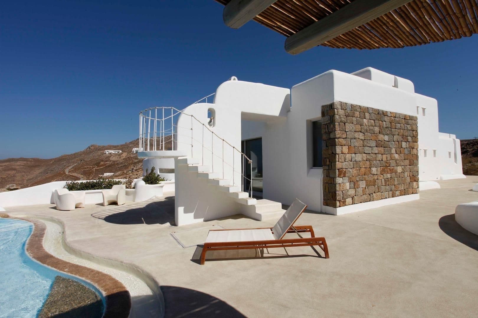 White cubist villa exterior with external staircase and stone accents