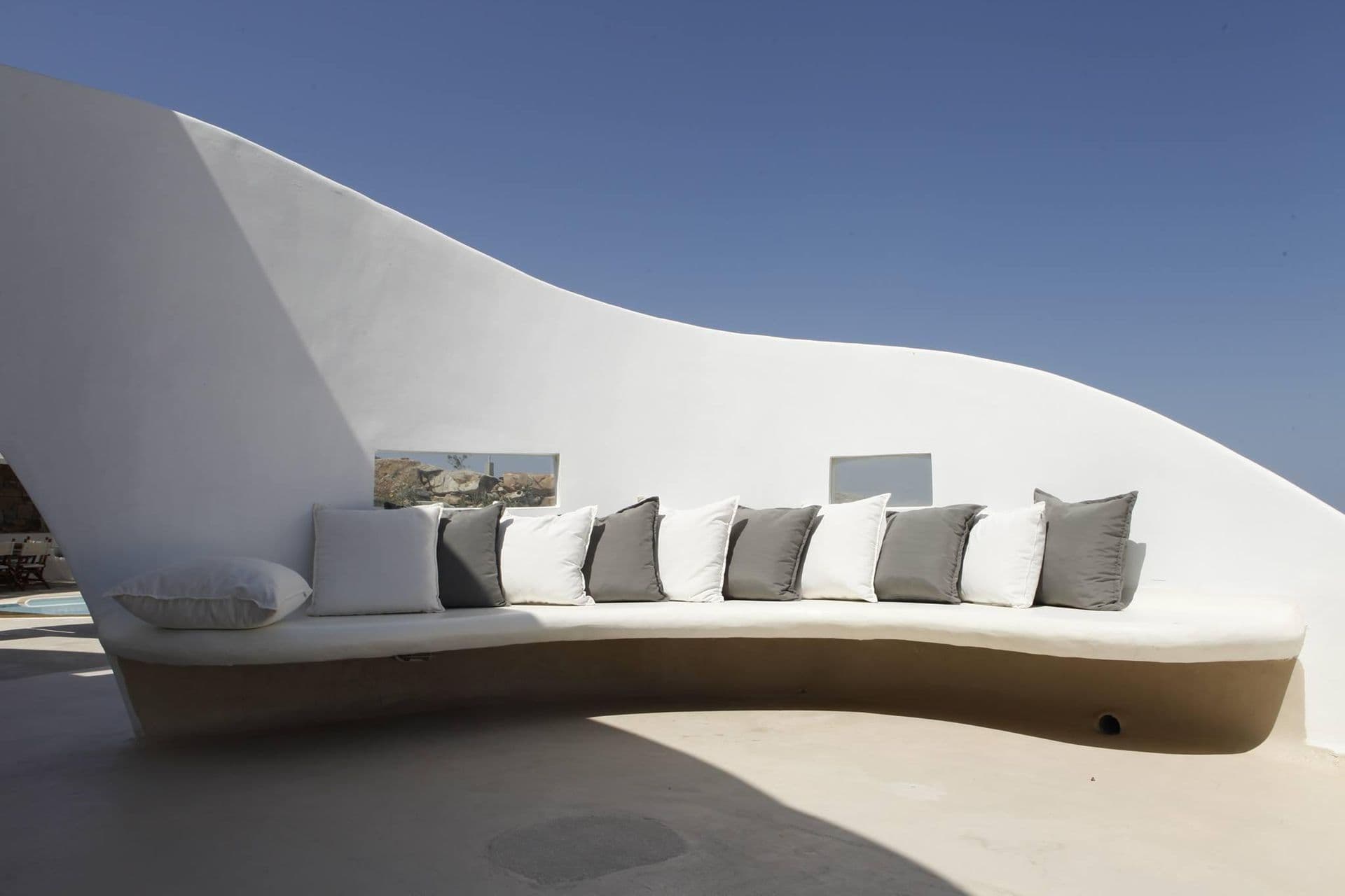 Wave-like curved white bench seating on a sunlit terrace
