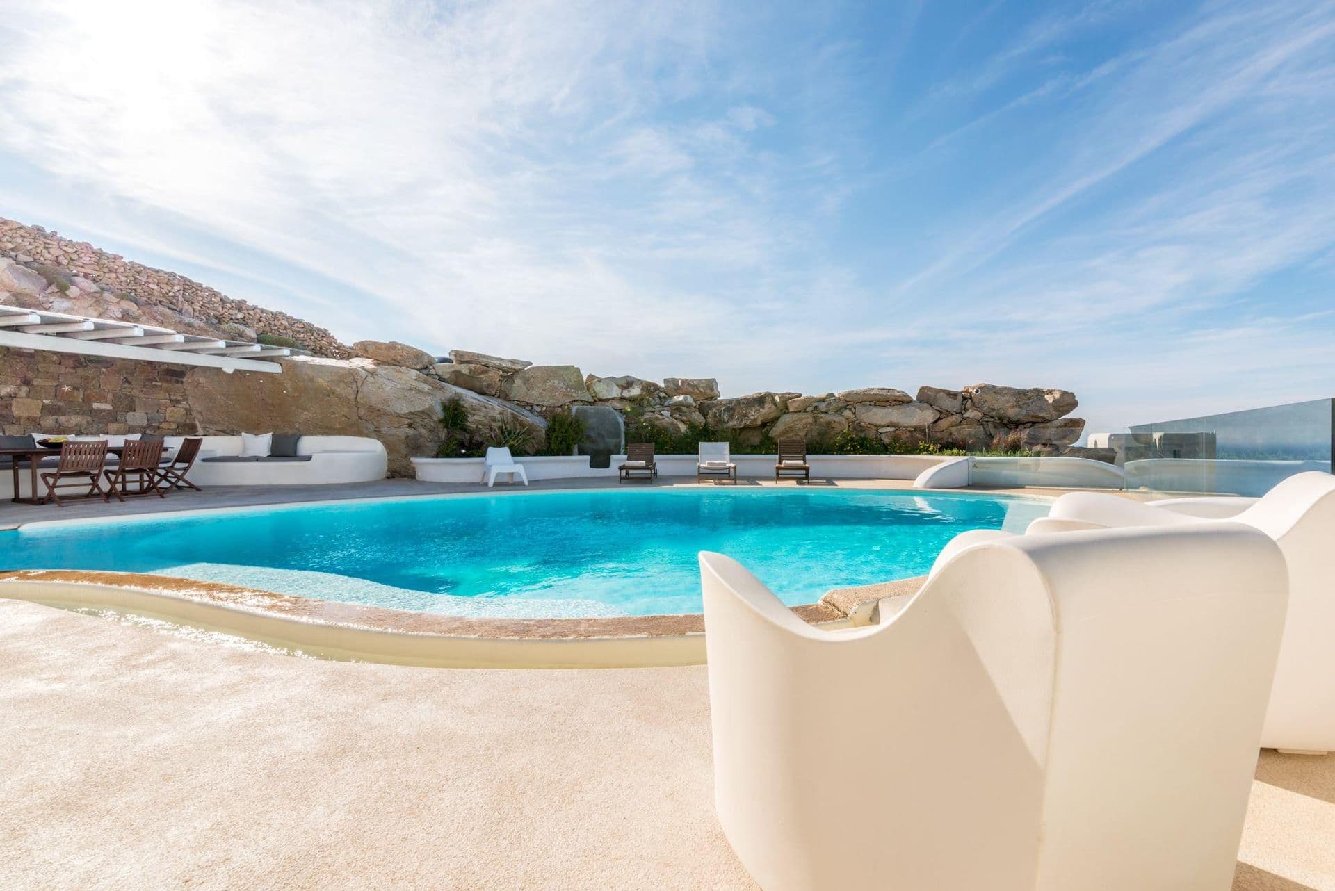 Curved pool terrace with sculptural white lounge chair and sea view