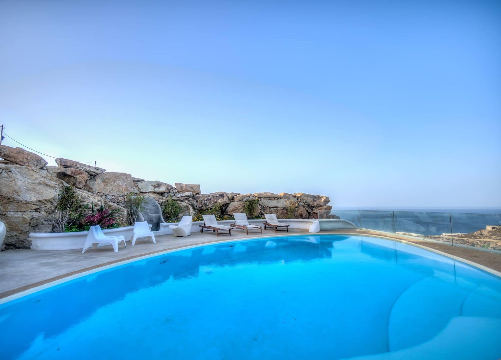 Bright blue pool set into a white stone terrace with sun loungers