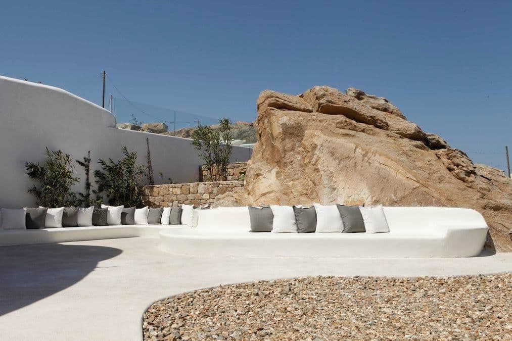 Built-in white lounge seating beside a natural rock outcrop on the terrace