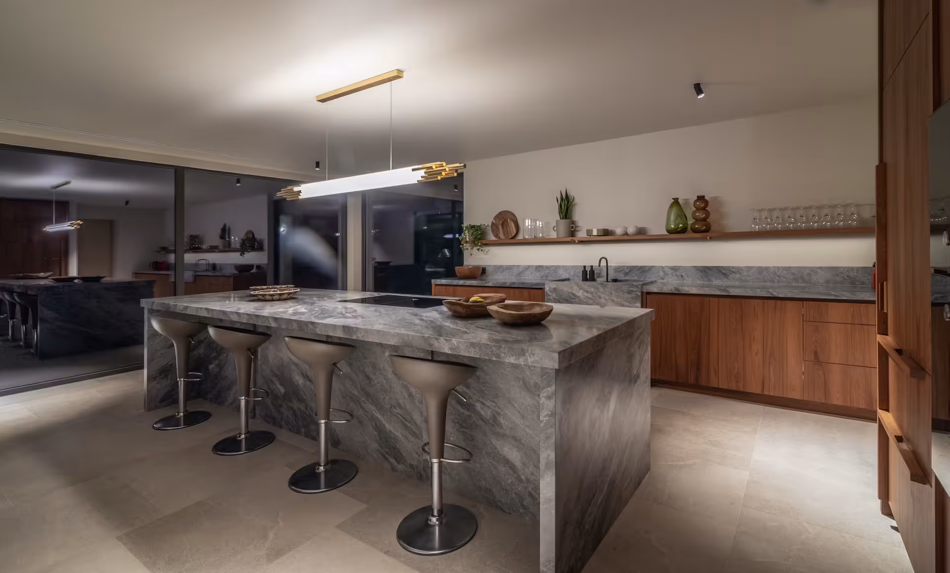 Dark stone kitchen island with bar stools beneath a concrete ceiling