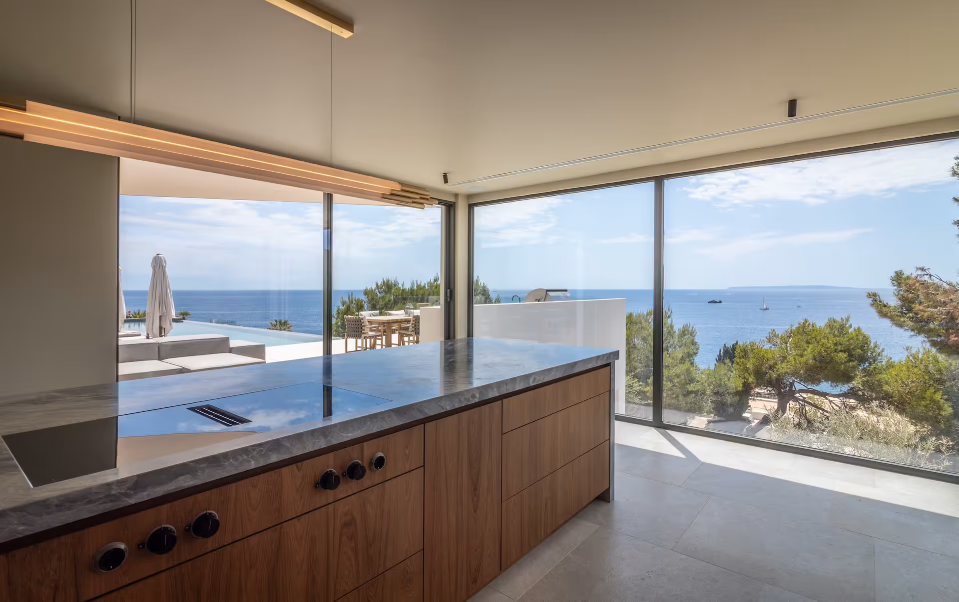Kitchen island beneath floor-to-ceiling glass with a panoramic coastal view