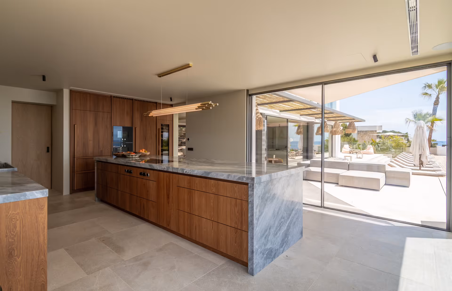Walnut kitchen cabinetry with an island overlooking the pool and sea