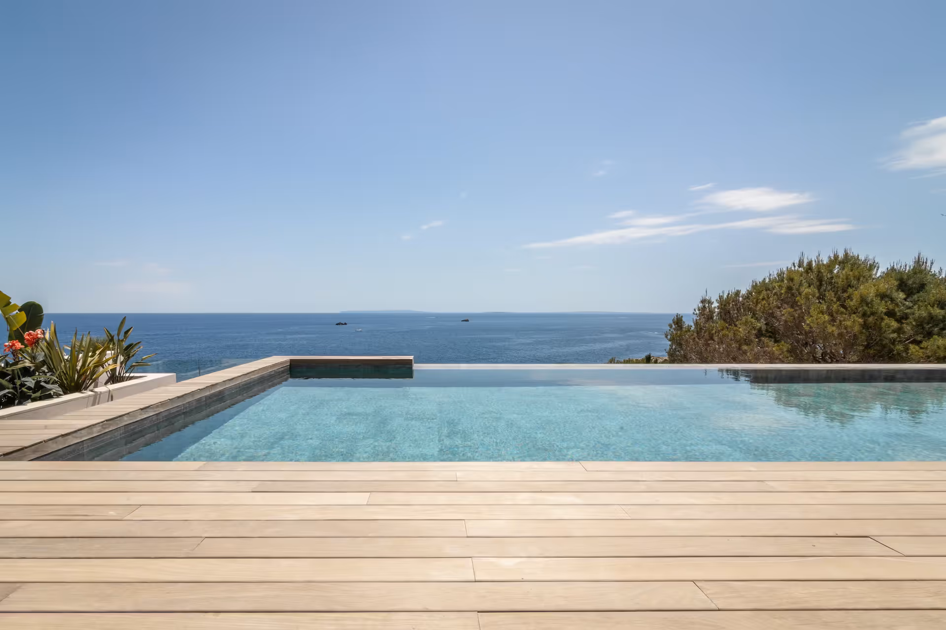 Infinity pool with timber deck stretching toward an uninterrupted sea horizon