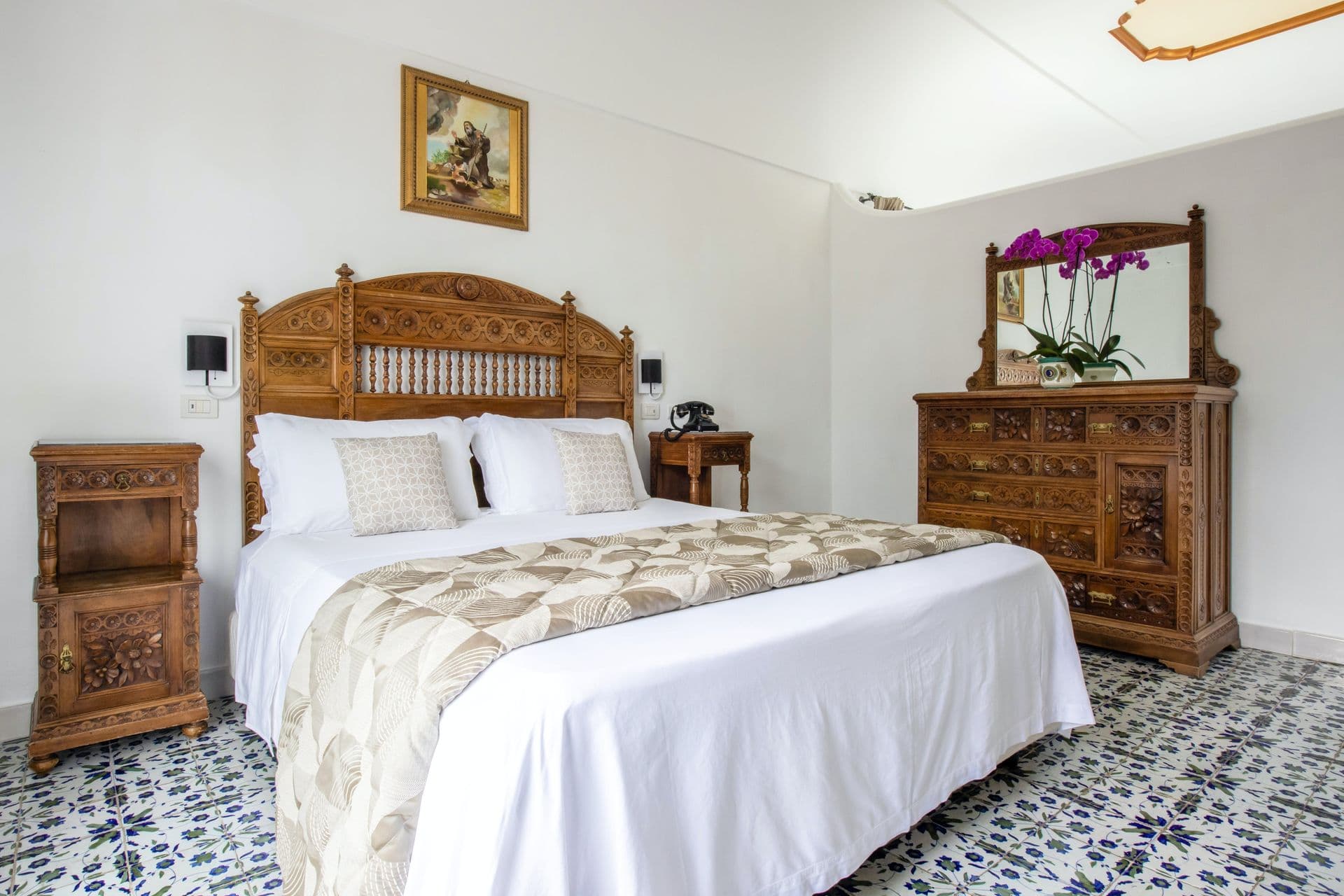 Antique-furnished bedroom suite with carved wooden headboard at Pavillion Paradiso