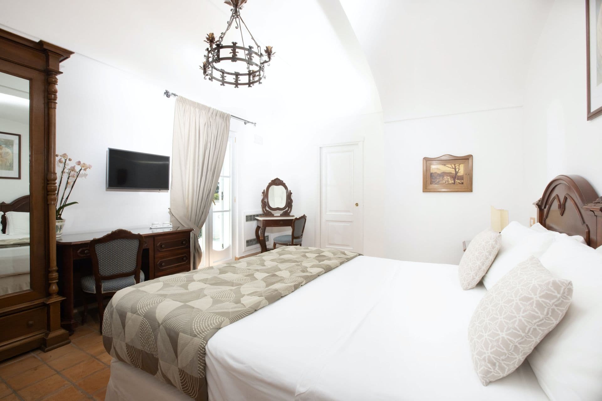 Bedroom with wrought-iron chandelier and antique dressing table at Pavillion Paradiso