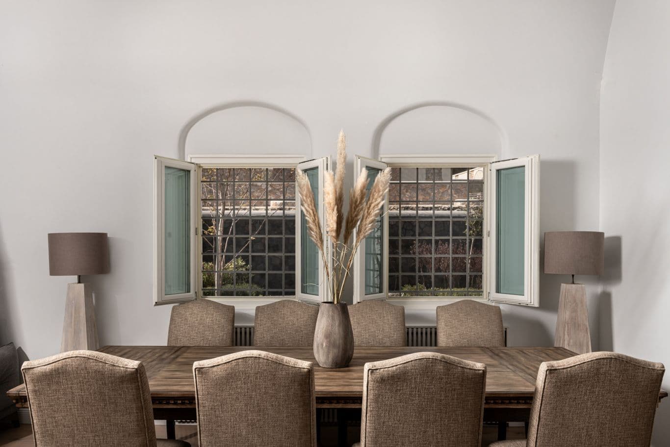 Dining room with arched twin windows and a rustic wooden table