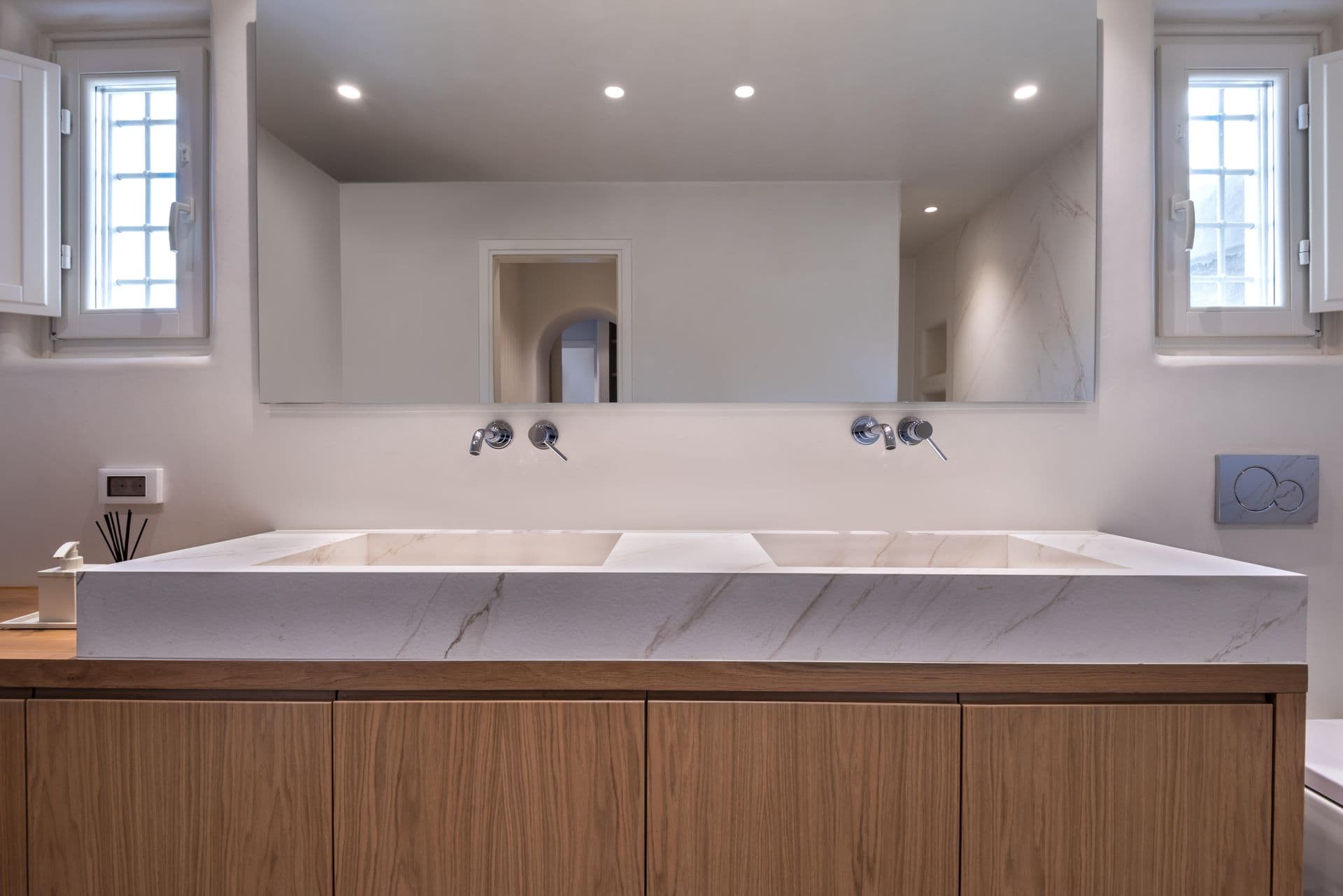 Marble double vanity bathroom with backlit mirror and wood-toned cabinetry
