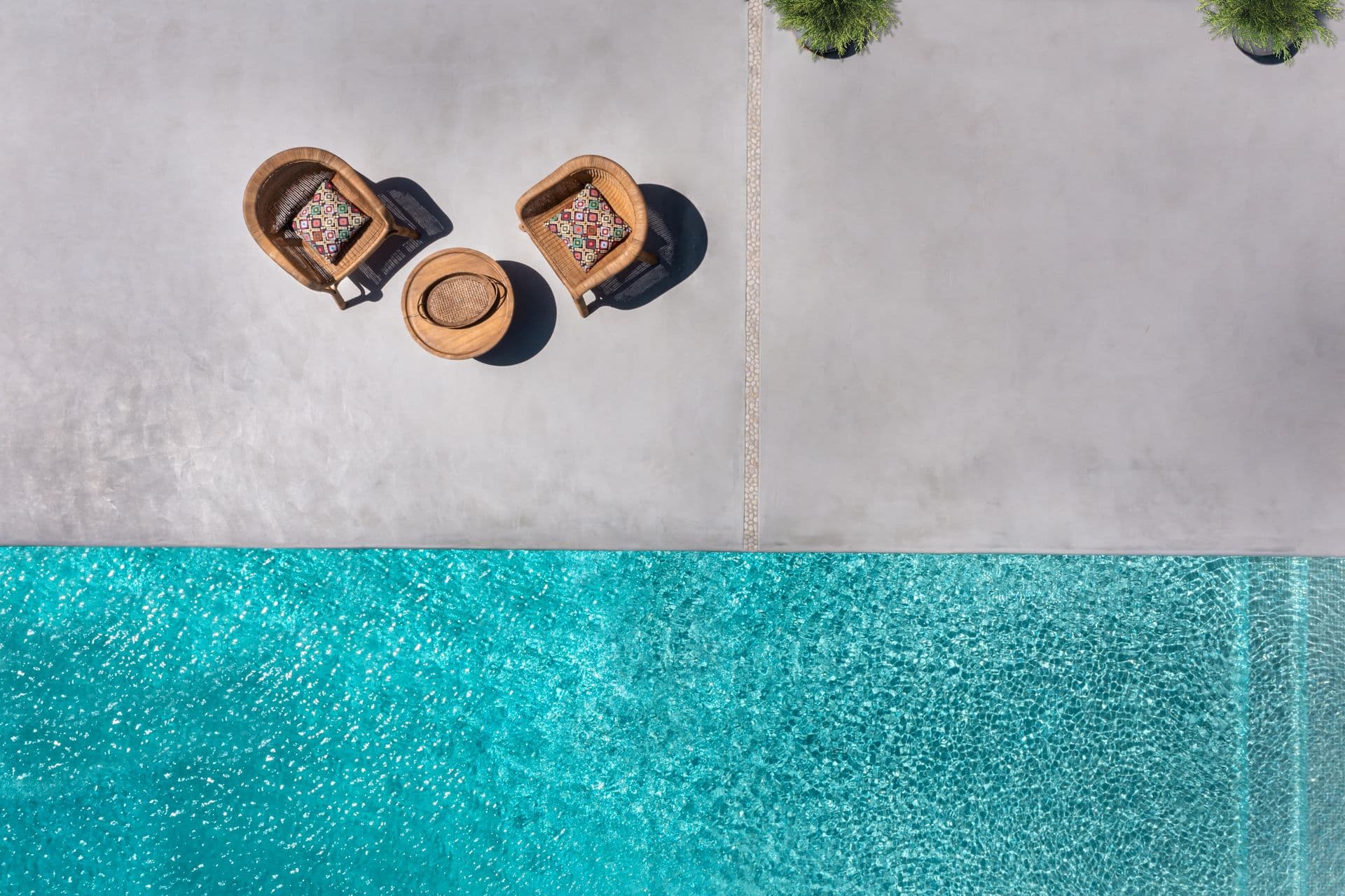 Aerial view of the turquoise infinity pool with rattan poolside chairs