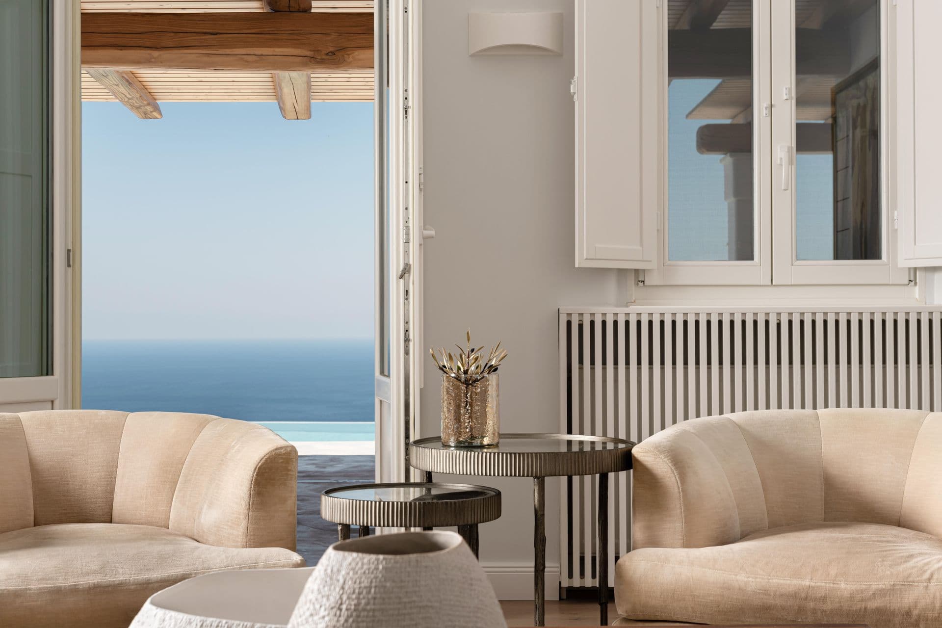 Cream armchair lounge beside a large window framing the sea