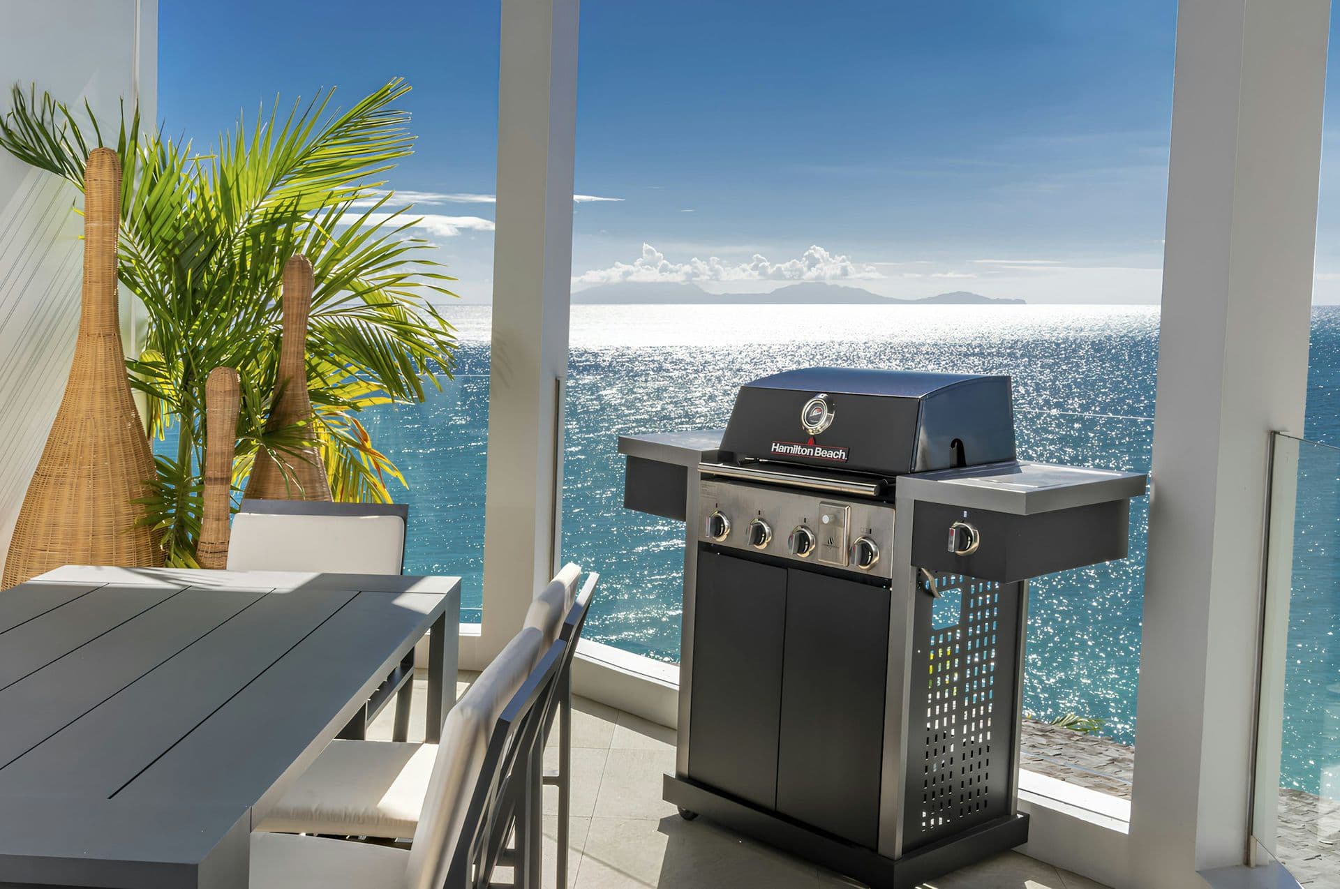 Terrace with a barbecue and dining table overlooking the sea at Life in the Palm
