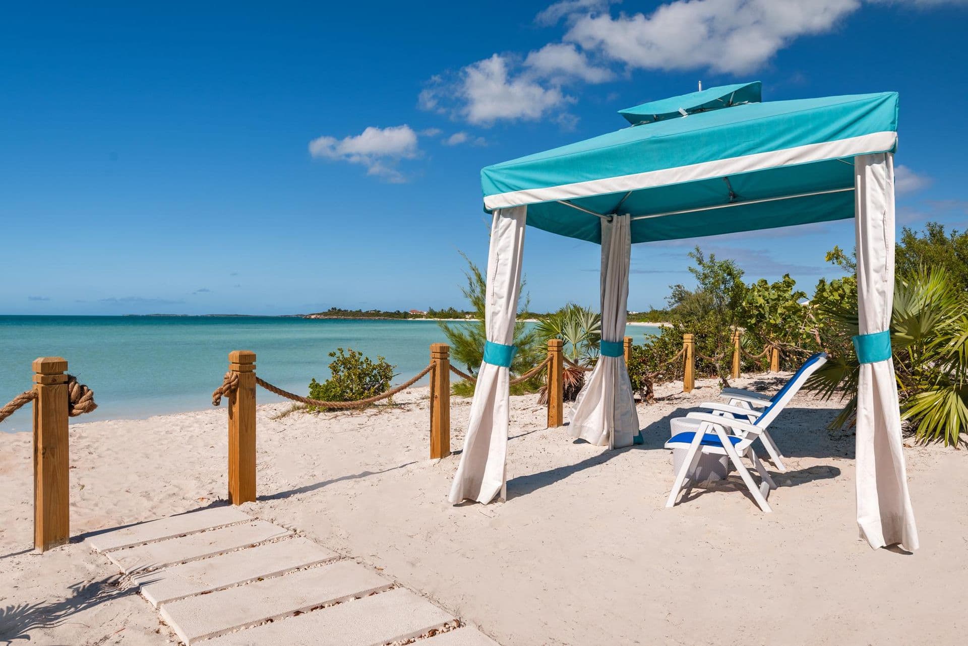 Private beach cabana with loungers on the white sand