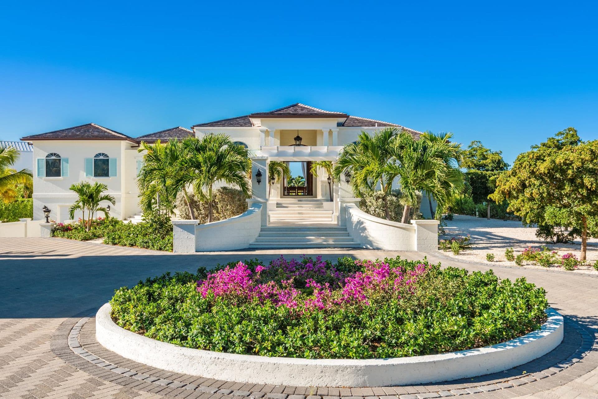 Palm-lined entrance driveway and facade of the villa