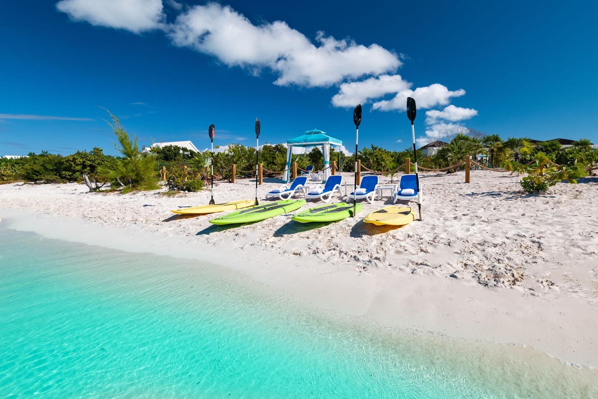 Kayaks and paddleboards ready on the private white-sand beach