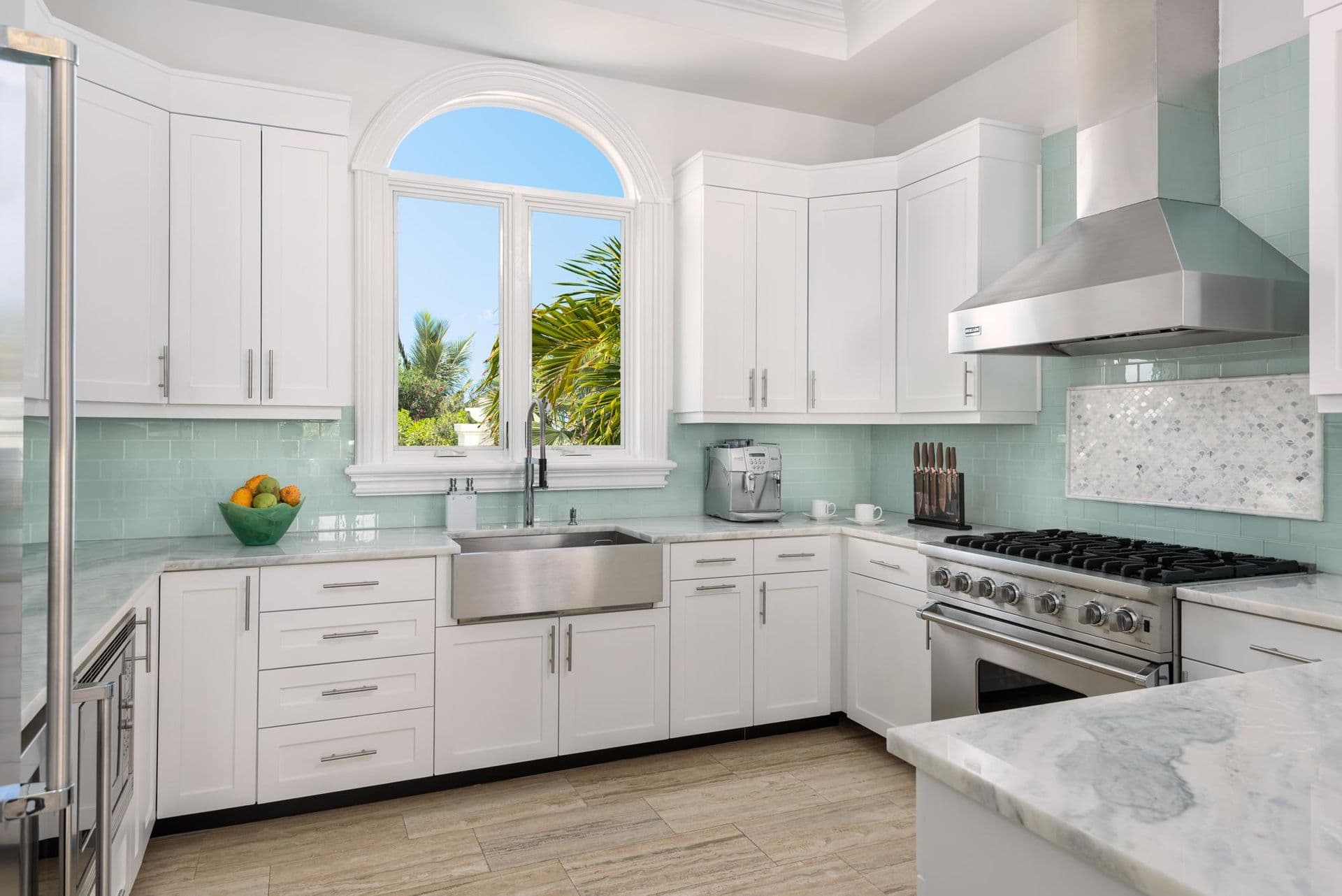 White gourmet kitchen with marble backsplash and stainless appliances