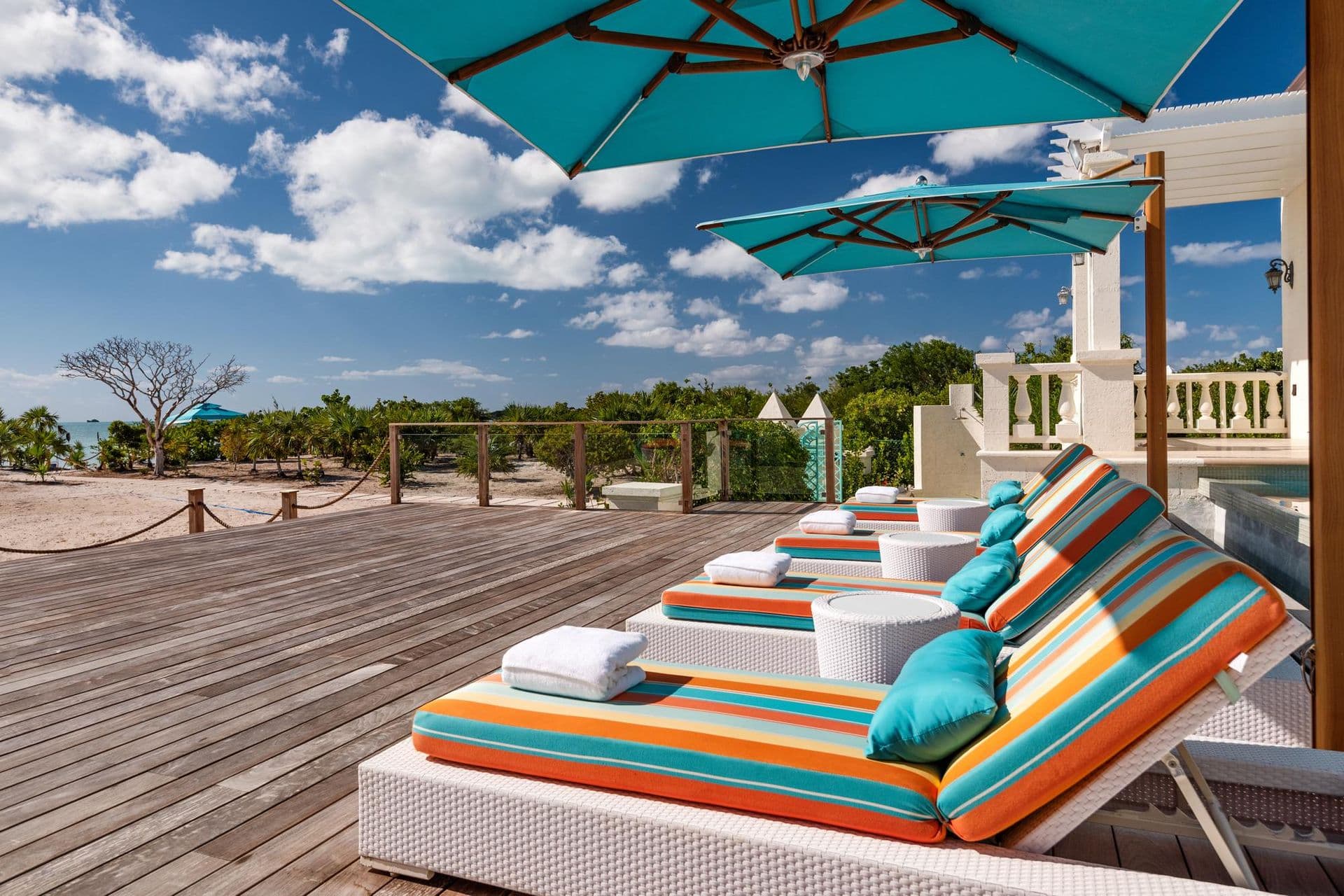 Wooden sun deck with striped loungers overlooking the coastline