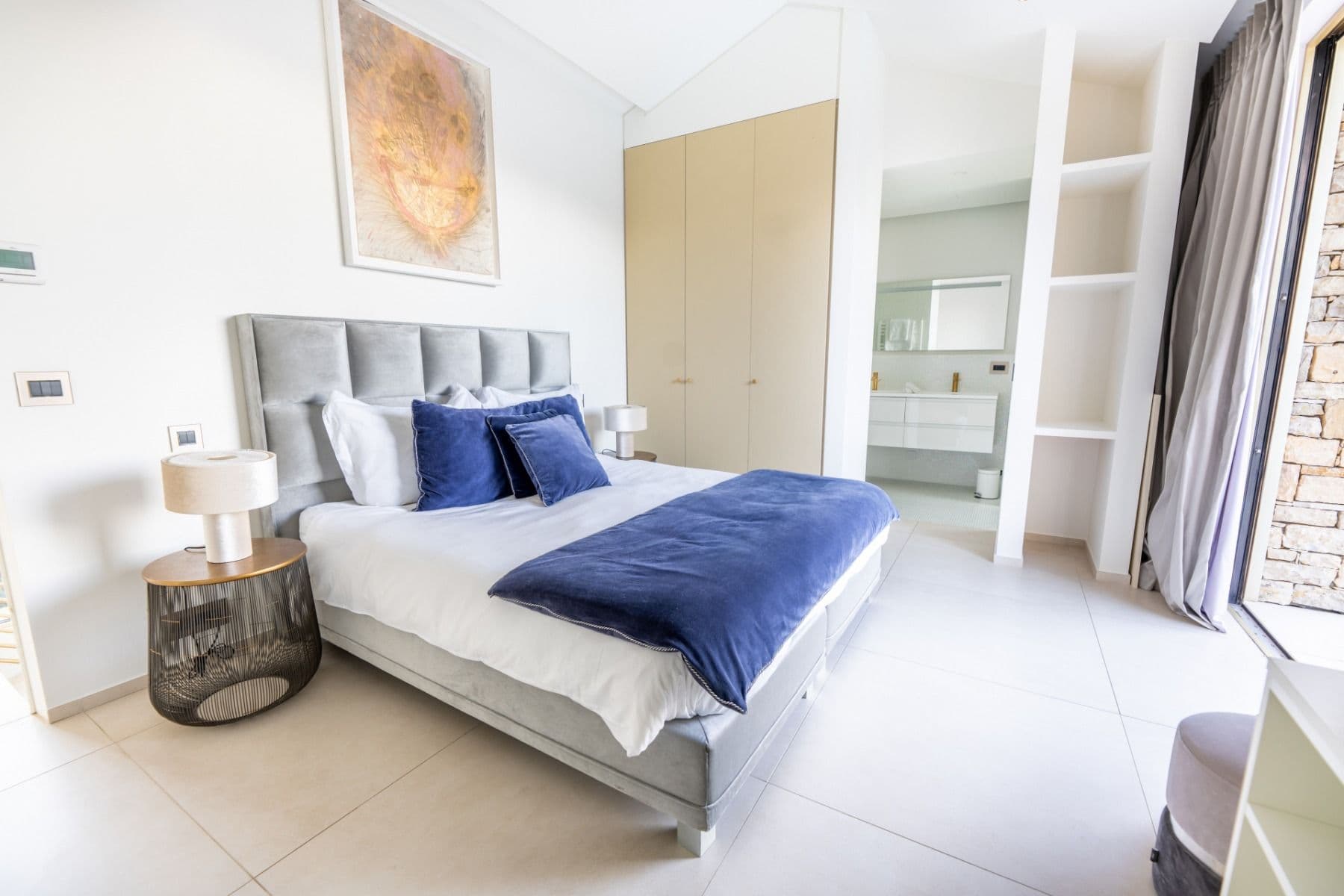 Bedroom with grey upholstered headboard, navy bedding and built-in wardrobe