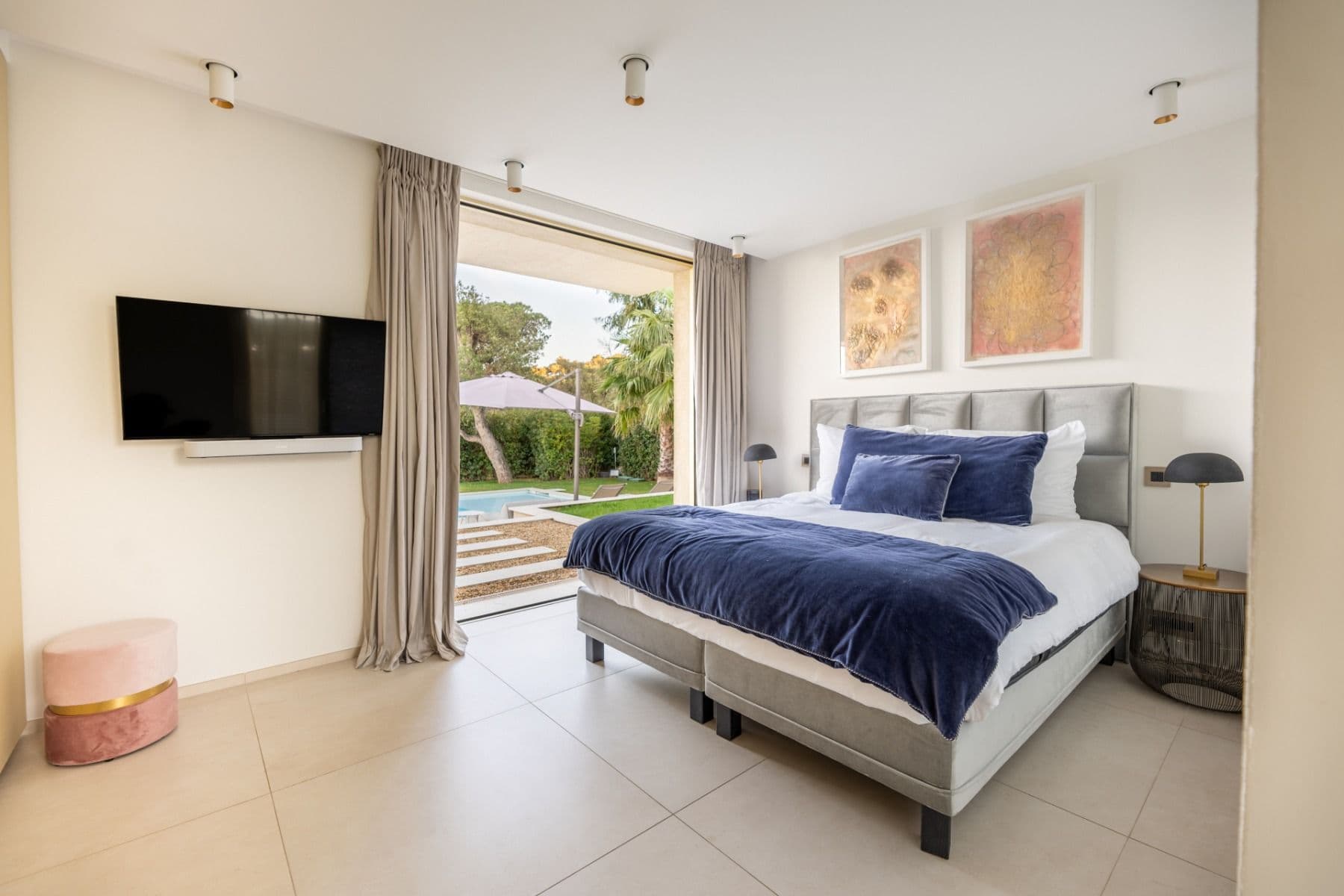 Bedroom with navy bed linen, wall-mounted television and garden-facing windows