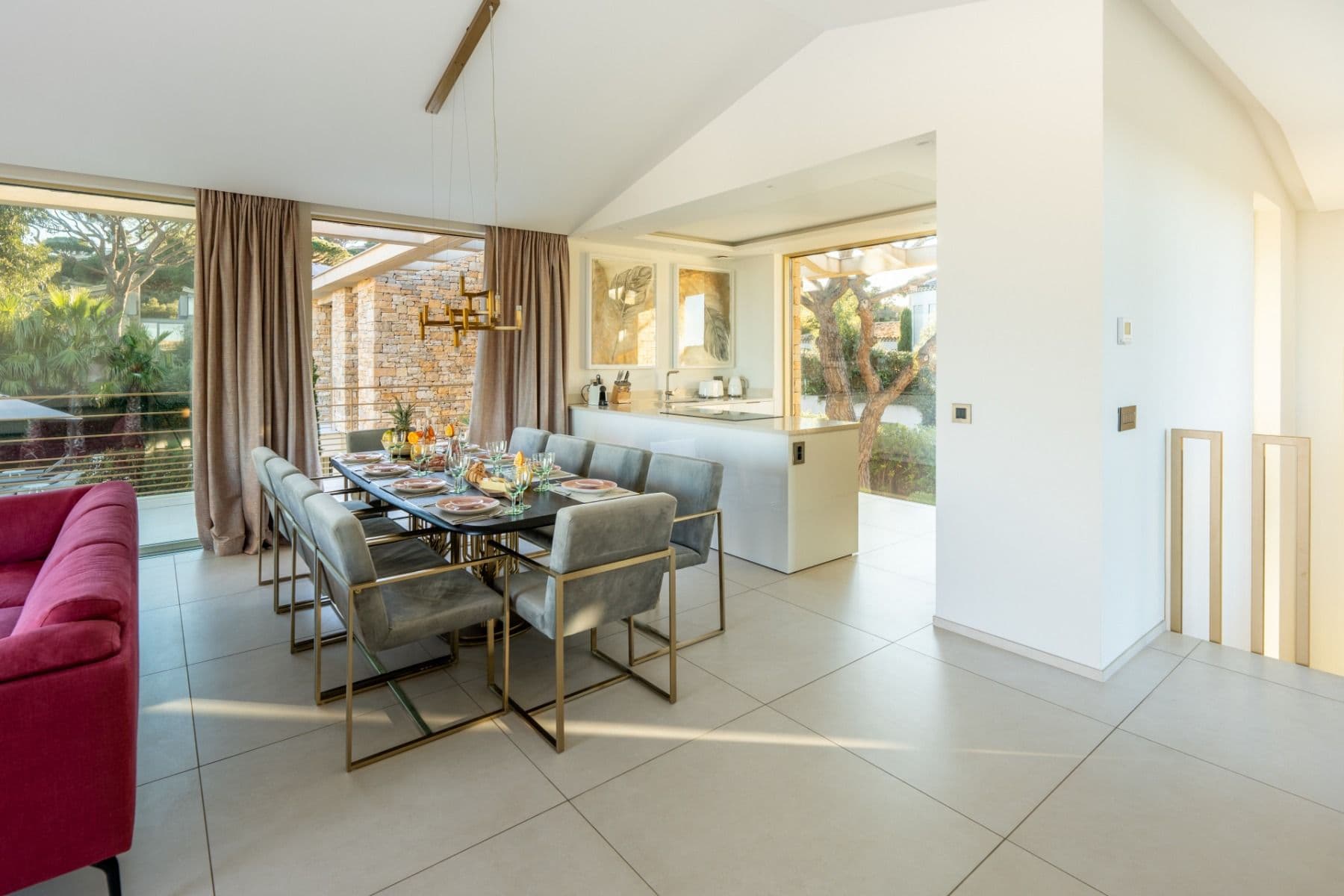 Dining table with red upholstered chairs opening onto the kitchen