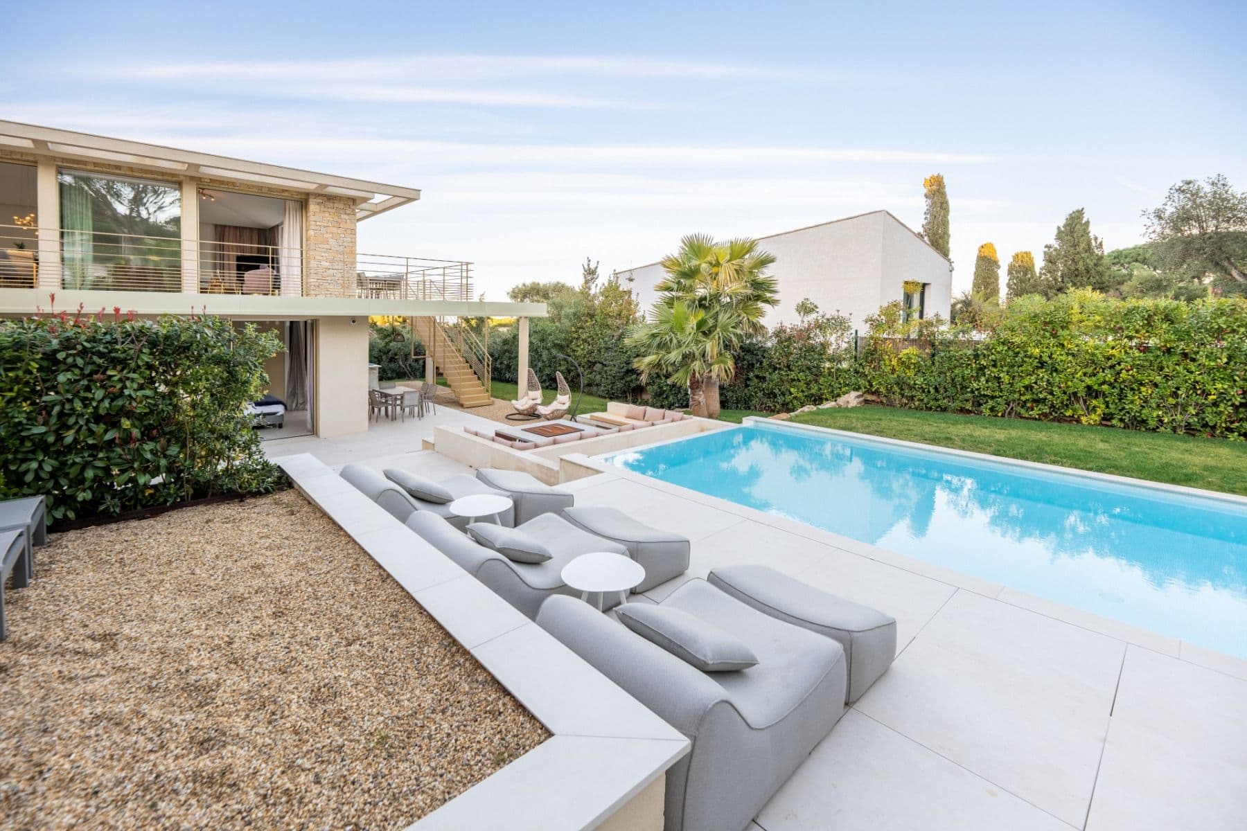 Swimming pool with sun loungers on a gravel terrace beside the stone-clad villa
