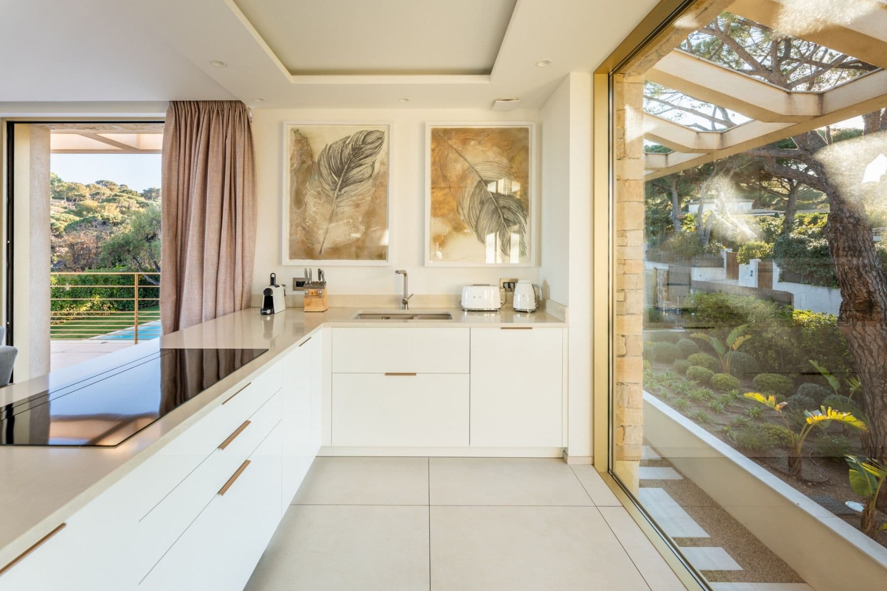White fitted kitchen with courtyard views through floor-to-ceiling glass