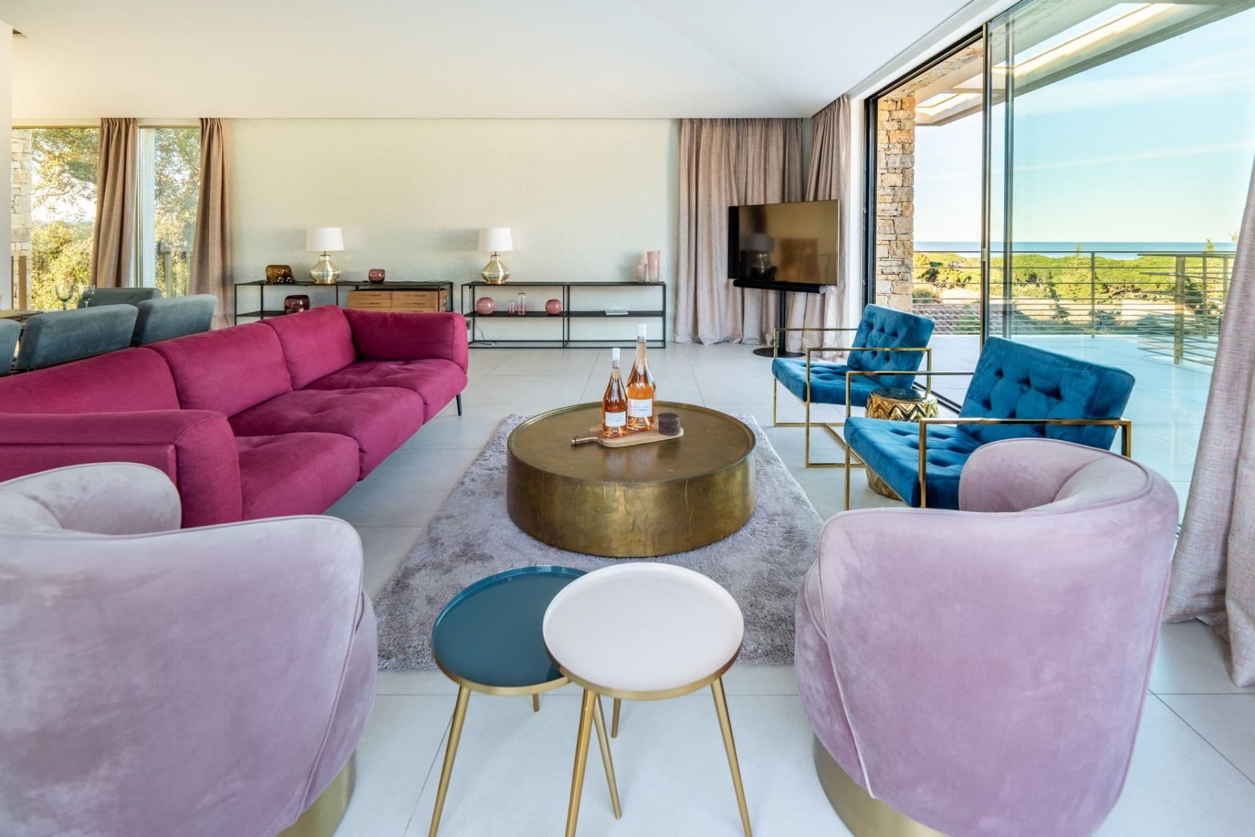 Living room with lavender velvet armchairs and a magenta sofa around a brass table