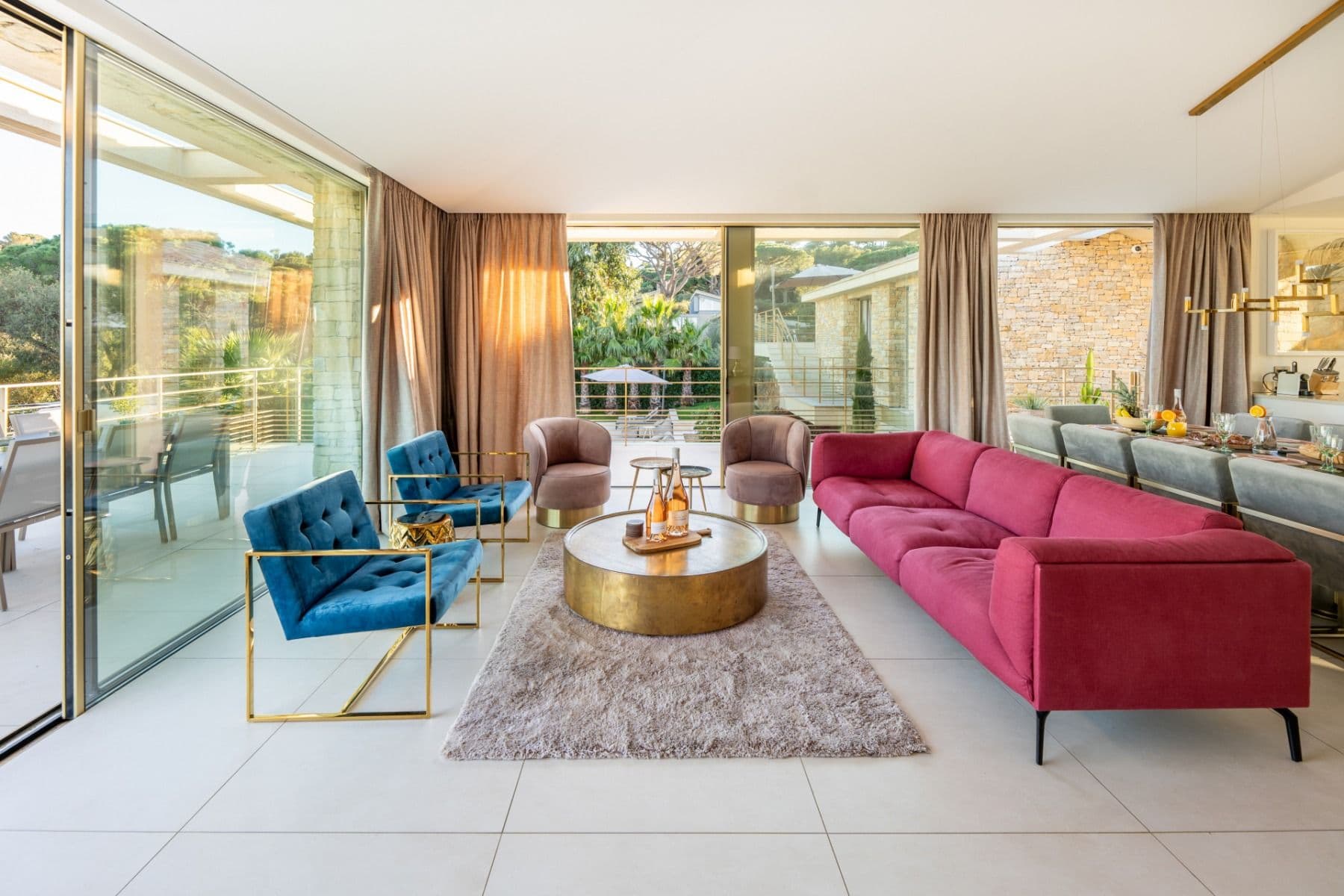 Living room with a red velvet sofa, blue accent chairs and glass doors onto the terrace