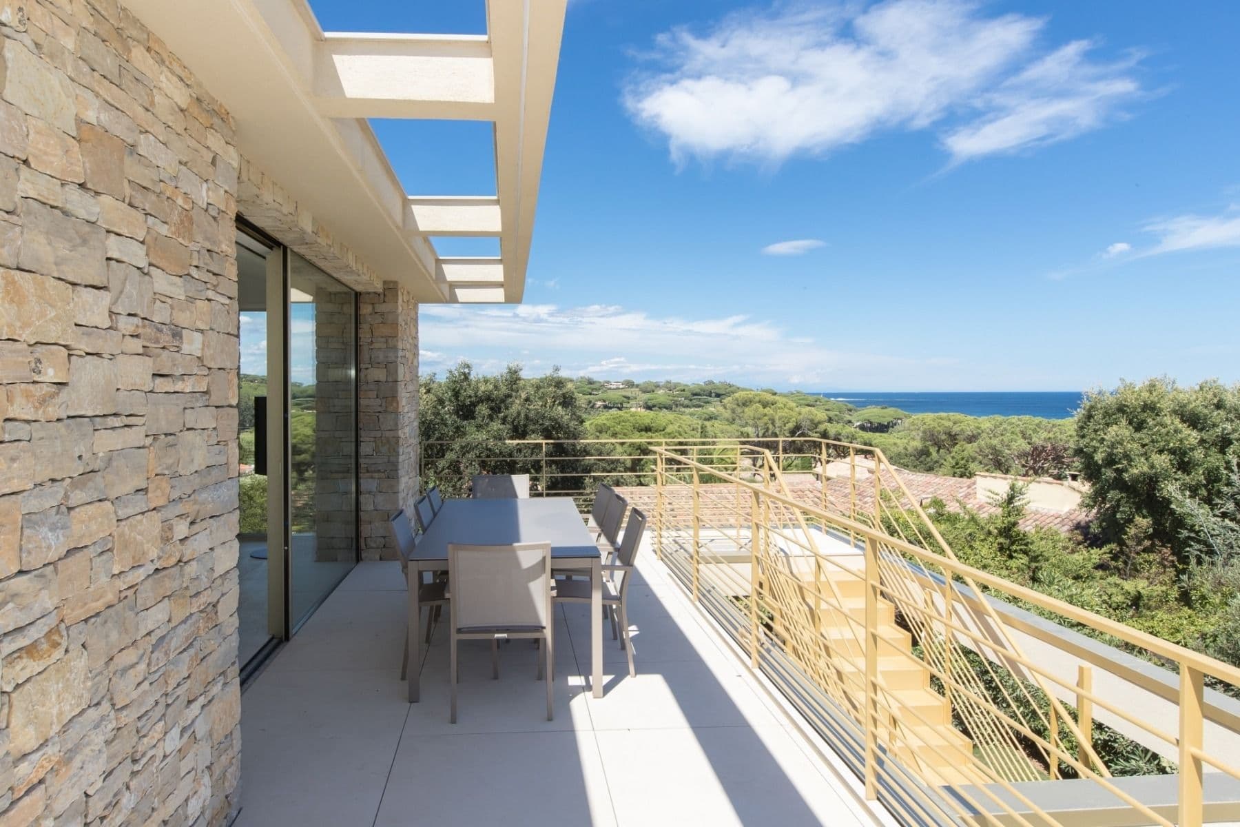 Stone-walled terrace with outdoor dining set and a distant sea view