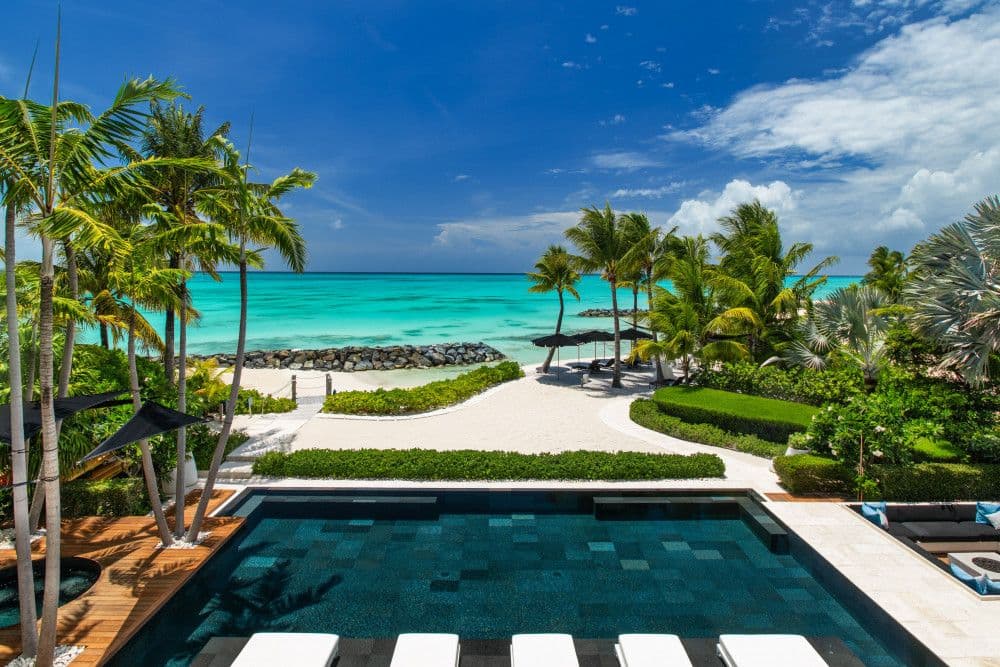 Dark-tiled infinity pool looking out over gardens to the turquoise sea at Villa Awa
