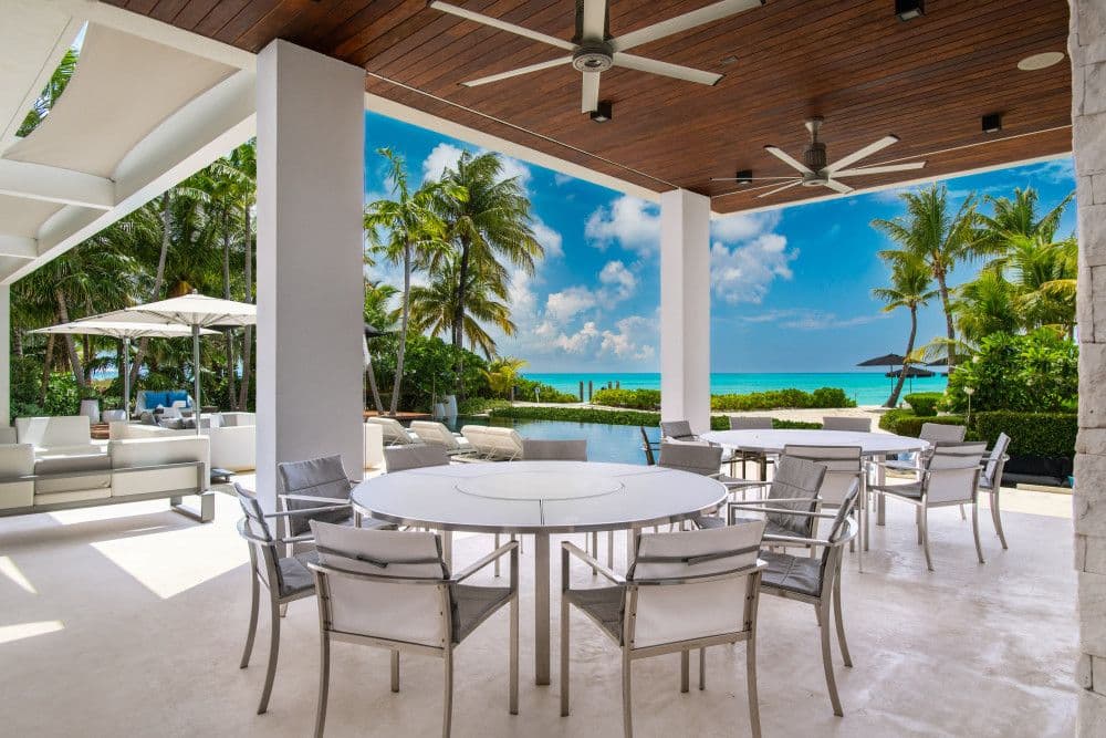 Covered terrace dining with round tables facing the ocean at Villa Awa