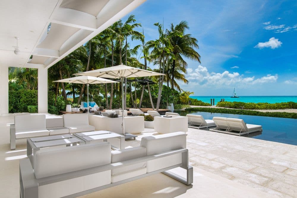 Covered terrace lounge beside the pool with ocean views at Villa Awa