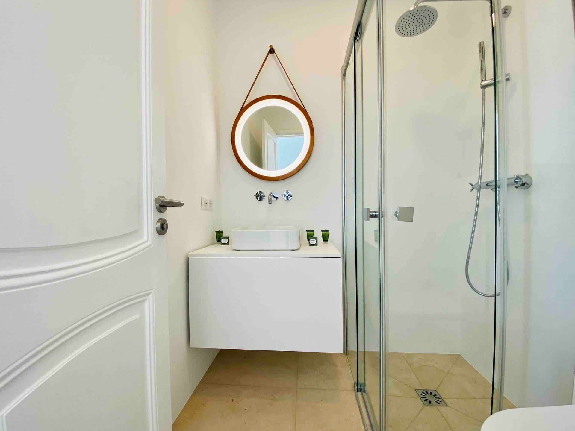 Bathroom with round mirror vanity and glass-enclosed shower
