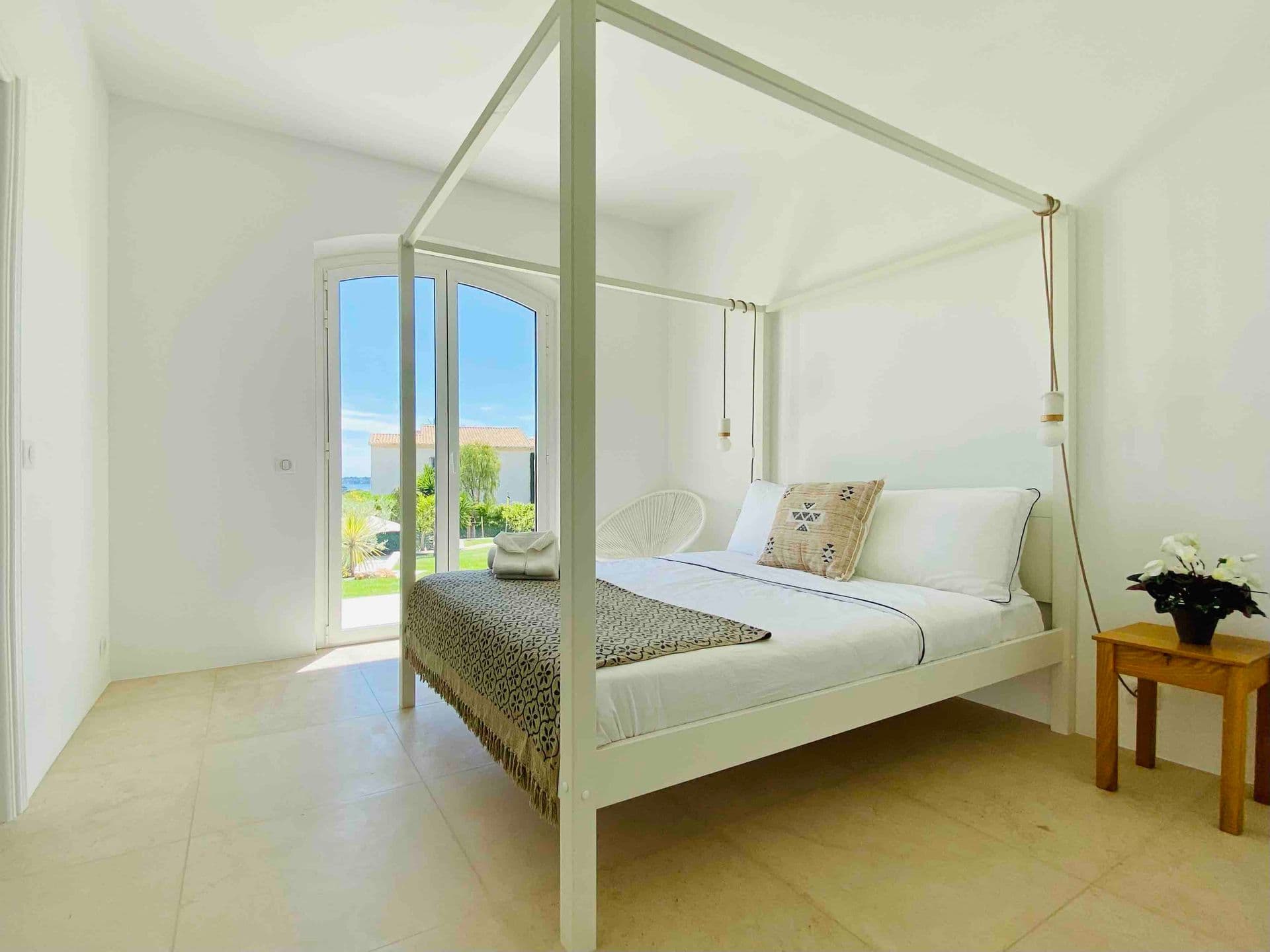 Bedroom with a white four-poster bed frame and garden view