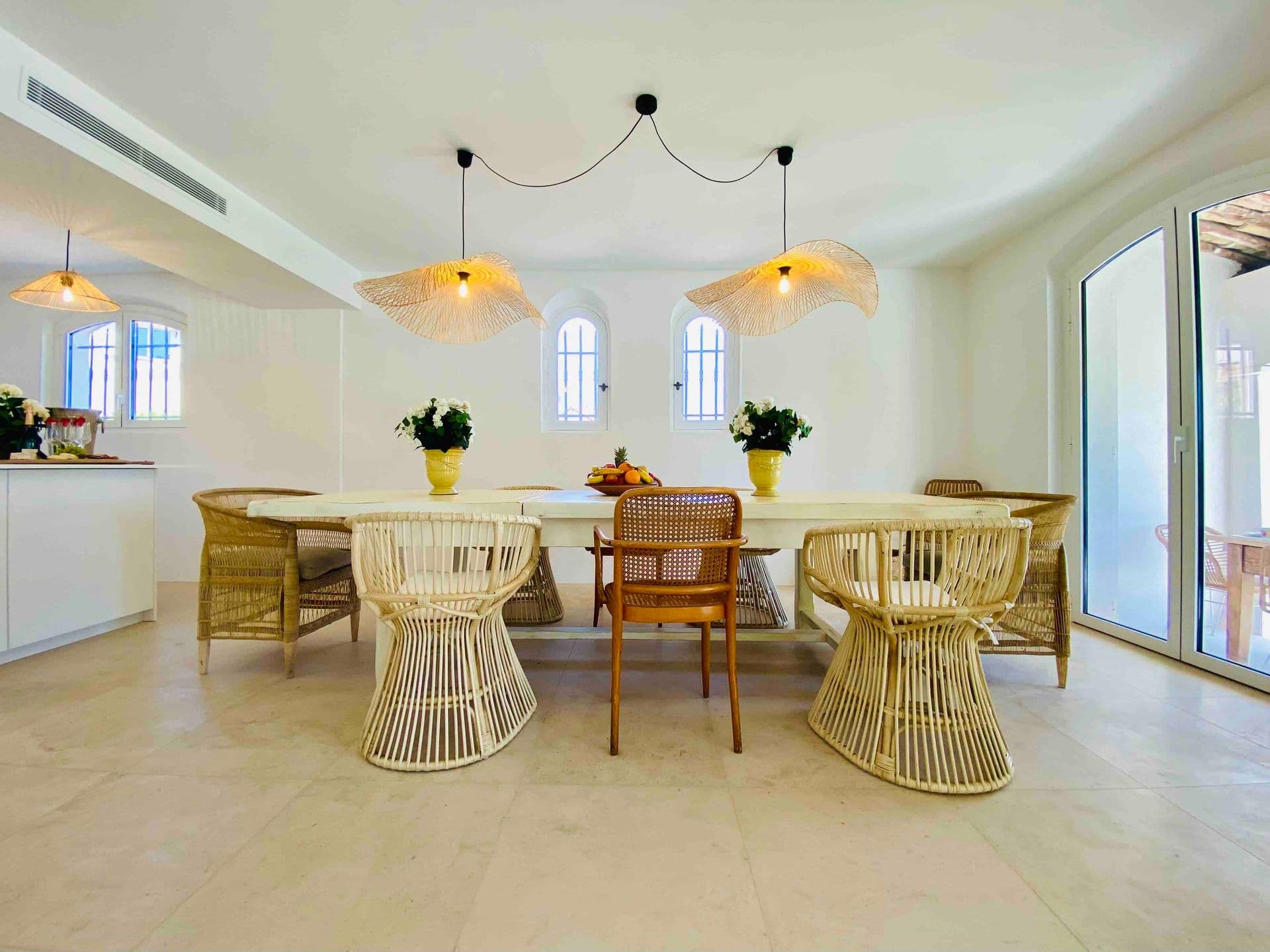 Dining area with rattan chairs beneath woven pendant lights