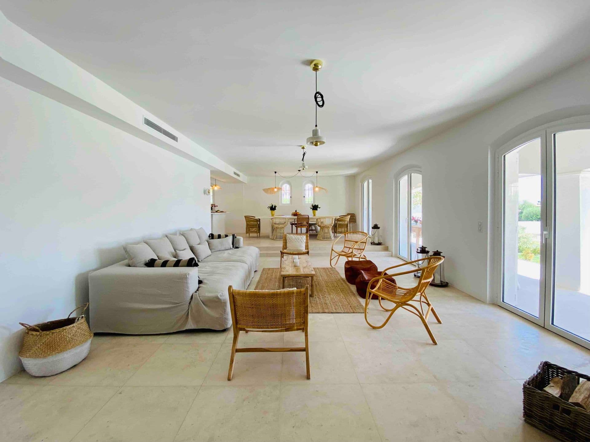 Bright living room with white sofa and rattan armchairs
