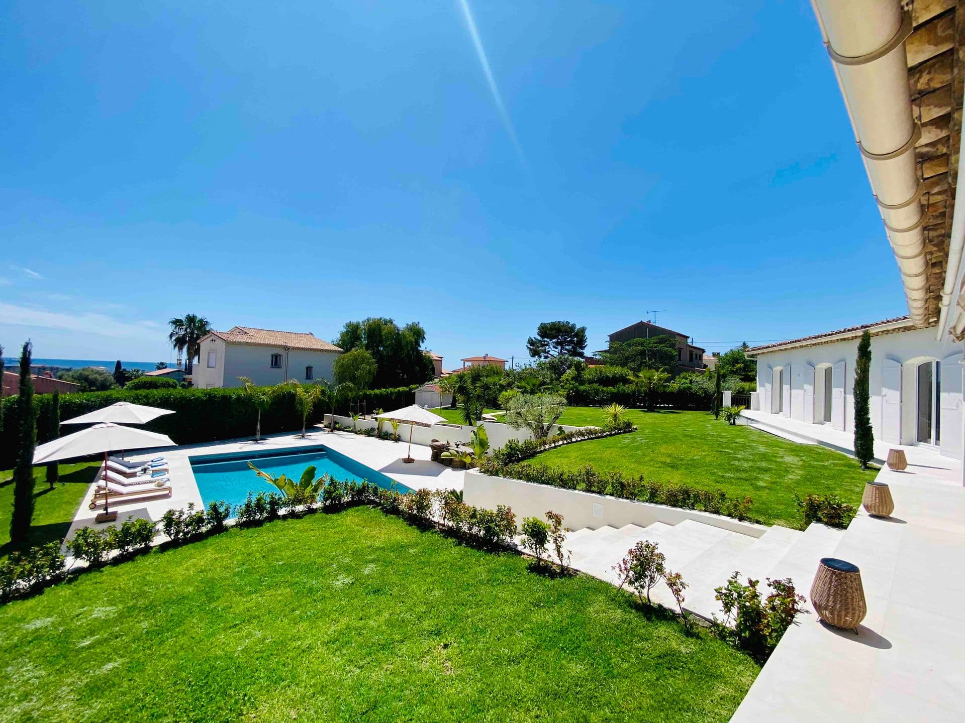 Wide view of the pool and lawned garden under a clear sky