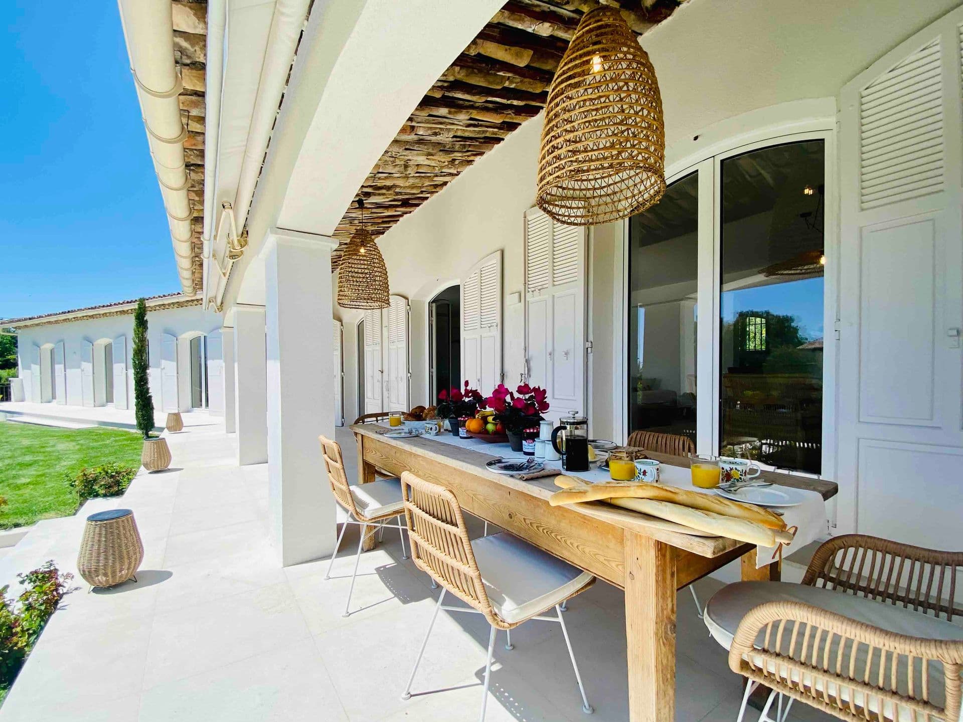 Covered terrace with a wooden dining table and rattan pendant lights