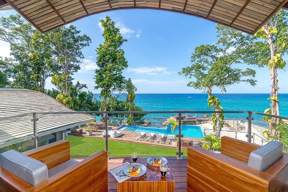 Covered balcony lounge overlooking the infinity pool and sea at Promiseas