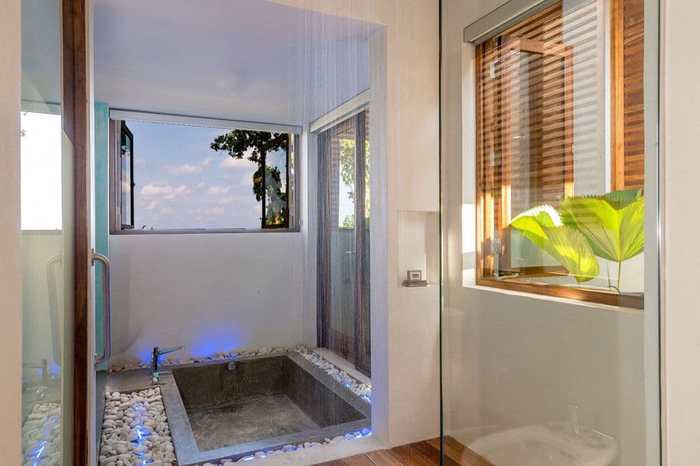 En-suite bathroom with a sunken stone tub set in pebbles at Promiseas