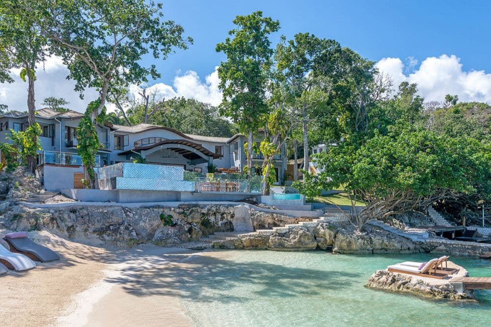 Promiseas seen from its private cove, with the villas above a sandy beach