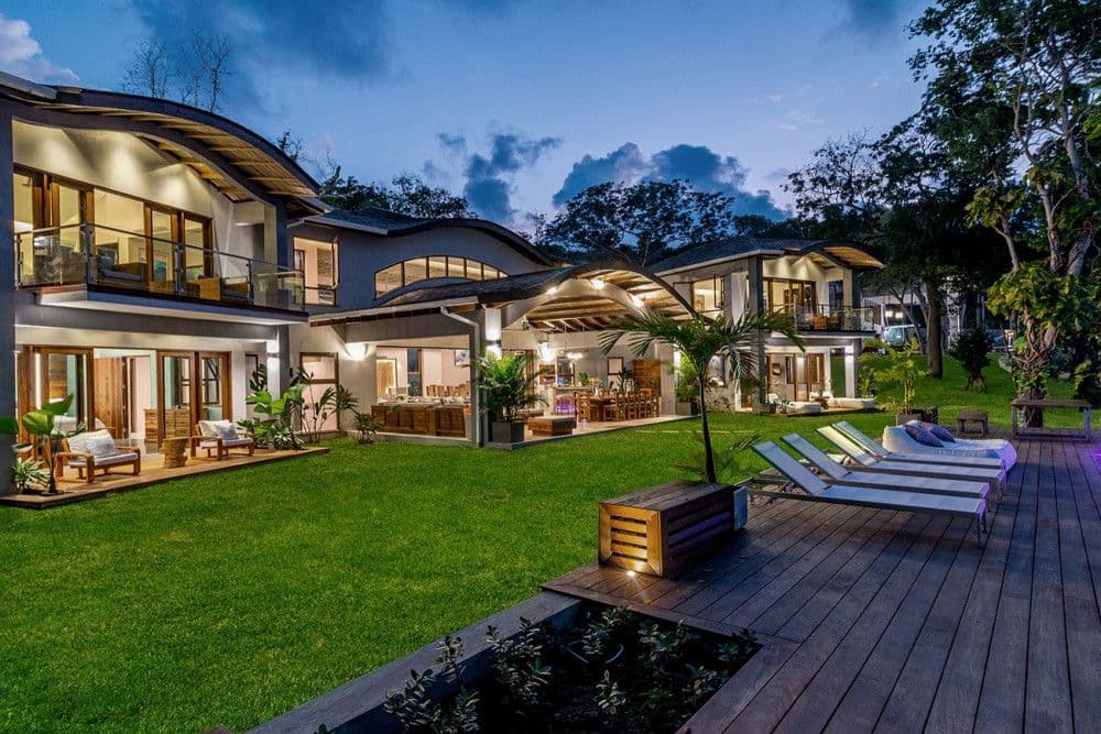 The two villas of Promiseas lit at dusk above the lawn and pool deck